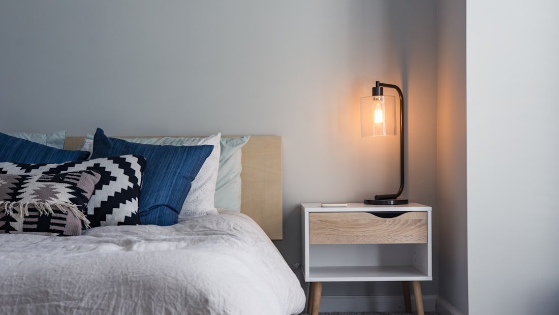 A neatly made bed in a dim, quiet bedroom