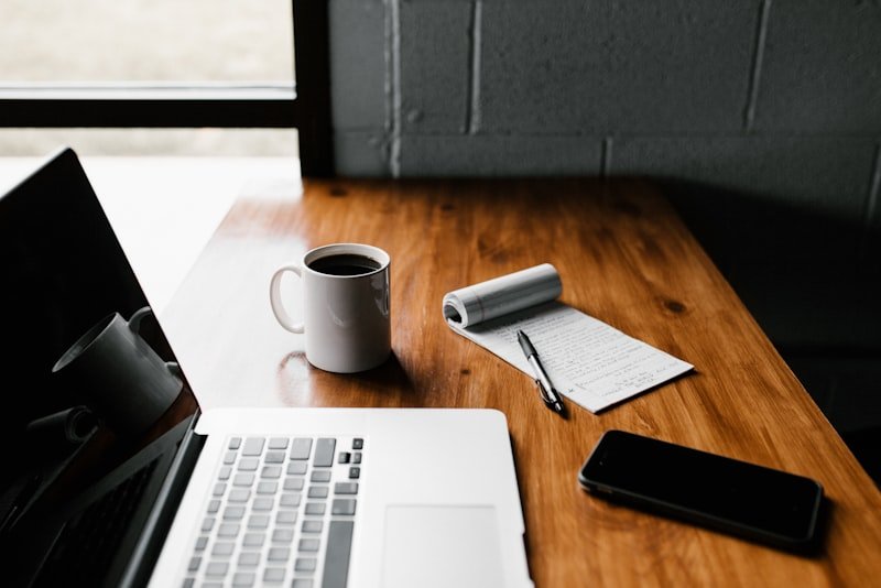 A quiet desk with coffee, an open notebook and morning light